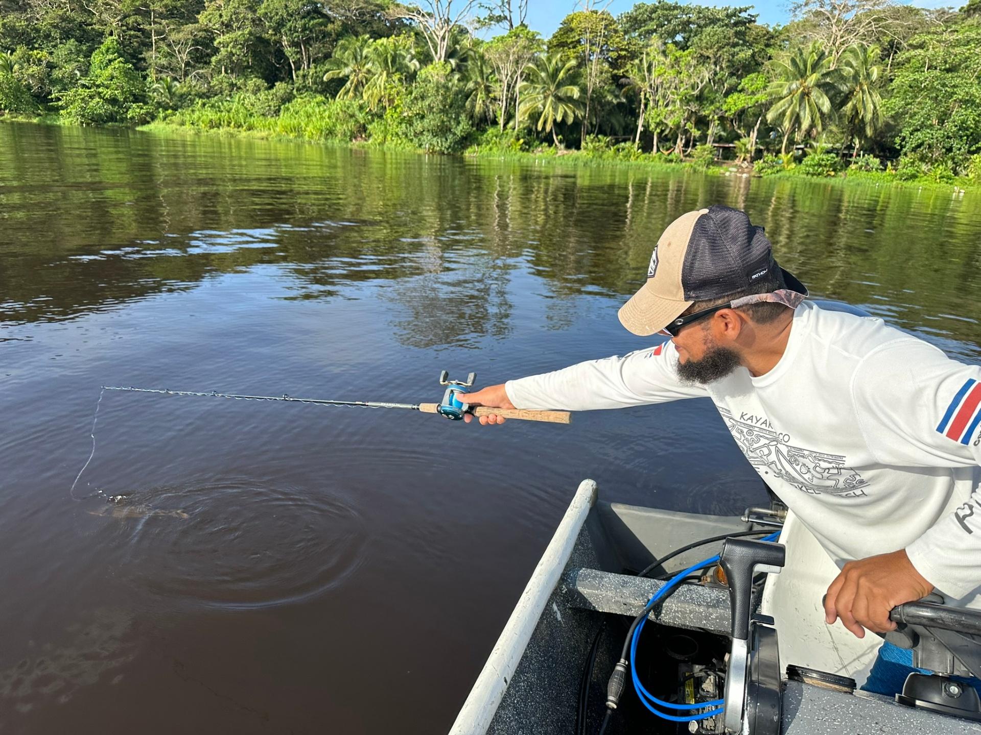 Fishing guide casting line on Tortuguero river surrounded by jungle
