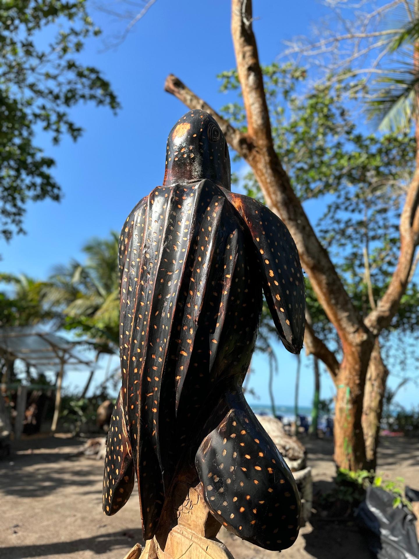 Wooden sea turtle sculpture with tropical backdrop